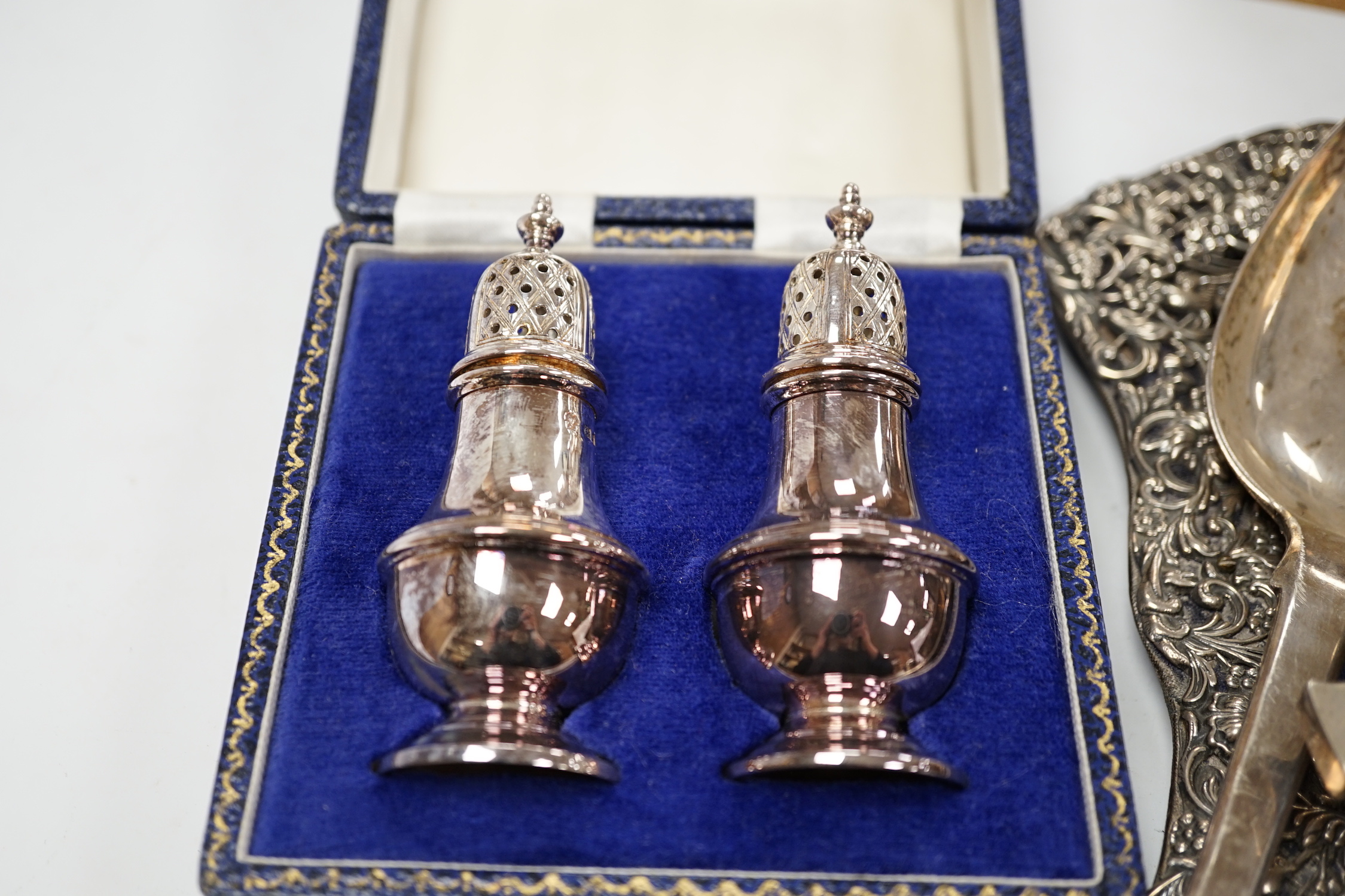 A quantity of silver items including a late Victorian repousse photograph frame, William Comyns, London, 1899, 20cm, three Georgian pepperettes, pair of small Armada dishes, quaich, vest case, menu holder, basting spoons